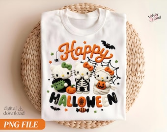May include: A white t-shirt featuring a graphic of three crocheted cat characters dressed for Halloween. The design includes the text Happy Halloween, a spider web, bats, and small pumpkins. The cats are dressed as a monster, a skeleton, and a mummy.
