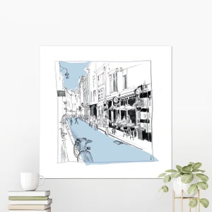 Peut inclure: Un croquis en noir et blanc d'une scène de rue avec des bâtiments, des personnes et un vélo. La rue est peinte en bleu clair.