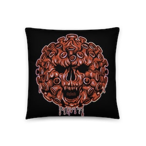 May include: A black pillow with a red and white illustration of a skull with spikes. The skull is surrounded by a circle of red spikes. The text "nighto" is written in white on the skull's mouth.