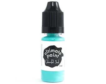 May include: A small bottle of turquoise blue paint with a black cap. The label reads "ultimate paint" and "Colourful Soul" with a black circle around the text. The bottle contains 9 ml of paint.