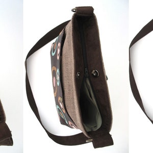 May include: A brown canvas shoulder bag with a zipper closure and a colorful geometric pattern. The bag has a brown strap and a beige lining.