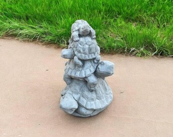 May include: A stack of four gray concrete turtle figurines. The turtles are stacked on top of each other, with the largest turtle at the bottom and the smallest turtle at the top.