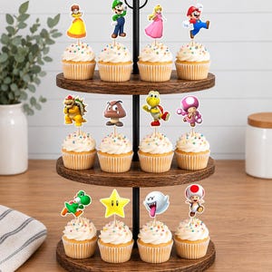 May include: A three-tiered wooden cupcake stand holding twelve cupcakes, each topped with a white frosting swirl and a colorful paper cutout of a Super Mario character, including Mario, Luigi, Princess Peach, Daisy, Bowser, Toad, and a star.