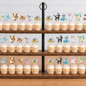 May include: A three-tiered wooden cupcake stand holding numerous cupcakes, each topped with a decorative paper cutout of various Eevee evolution characters. The stand features a central black metal pole and a dark wood grain finish on the shelves.