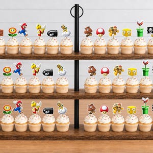 May include: A three-tiered wooden stand holding numerous cupcakes, each topped with a decorative paper cutout featuring various Super Mario characters and icons, including Mario, Goombas, mushrooms, question blocks, and piranha plants.