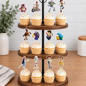 Puede incluir: Un soporte de madera para cupcakes de tres niveles con doce cupcakes, cada uno cubierto con un remolino de glaseado blanco, chispas de colores y un recorte de papel de un personaje de Toy Story, incluyendo a Woody, Buzz Lightyear y Forky.