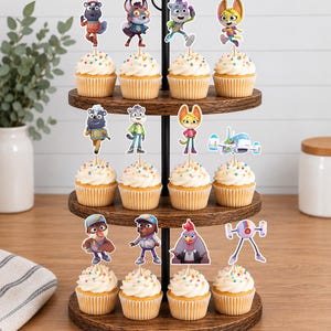 Puede incluir: Un soporte de madera para cupcakes de tres niveles con doce cupcakes cubiertos de glaseado blanco y chispas de colores. Cada cupcake tiene un adorno de papel decorativo que representa varios personajes de animales y un peque&ntilde;o veh&iacute;culo futurista.