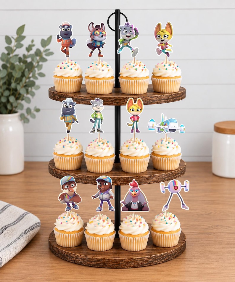 Puede incluir: Un soporte de madera para cupcakes de tres niveles con doce cupcakes cubiertos de glaseado blanco y chispas de colores. Cada cupcake tiene un adorno de papel decorativo que representa varios personajes de animales y un peque&ntilde;o veh&iacute;culo futurista.