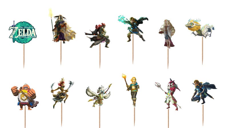 May include: A selection of cake toppers featuring characters from The Legend of Zelda: Tears of the Kingdom. The toppers show various characters in action poses, with detailed costumes and accessories. The toppers are mounted on wooden sticks.