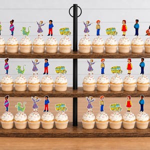 May include: A three-tiered wooden stand holding rows of cupcakes topped with colorful paper cutouts of cartoon characters, including children, a green creature, and a yellow school bus, arranged in repeating patterns across all three levels.