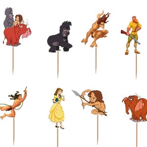 May include: A set of twelve decorative cupcake toppers featuring various animated characters and the word Tarzan. Each cutout is attached to a thin wooden pick. The collection includes figures of gorillas, a leopard, a man with a rifle, and a woman.
