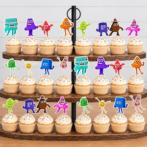 May include: A three-tiered wooden cupcake stand holding twenty-four cupcakes, each topped with a colorful, cartoon-style character cutout. The characters include various shapes and colors like blue, purple, red, orange, green, and brown figures.
