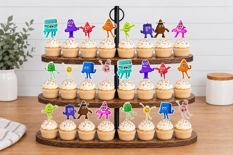 May include: A three-tiered wooden cupcake stand holding twenty-four cupcakes, each topped with a colorful, cartoon-style character cutout. The characters include various shapes and colors like blue, purple, red, orange, green, and brown figures.