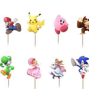 May include: A set of twelve decorative cupcake toppers featuring various video game characters including Link, Mario, Pikachu, Kirby, Donkey Kong, Samus, Fox, Yoshi, Peach, Zelda, Sonic, and Bowser, each attached to a thin wooden toothpick.