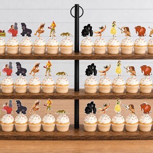May include: A three-tiered wooden cupcake stand holding numerous cupcakes topped with paper cutouts of Tarzan characters, including Tarzan, Jane, gorillas, and other jungle animals, with a Tarzan logo sign on the left side of each tier.