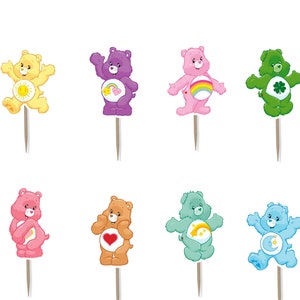May include: A collection of Care Bears cupcake toppers in various colors, including yellow, purple, pink, green, and blue. Each bear has a unique design on its belly and is attached to a wooden pick. Some toppers feature rainbows and clouds.