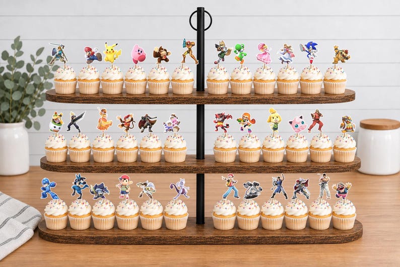 May include: A three-tiered wooden cupcake stand holding numerous cupcakes, each topped with a unique paper cutout of a video game character. The characters include various figures from popular gaming franchises, arranged across the three shelves.