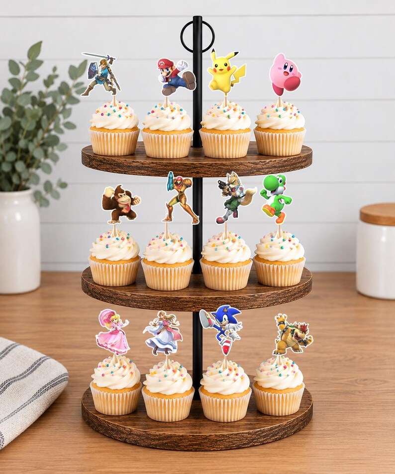 May include: A three-tiered wooden cupcake stand holding twelve cupcakes, each topped with a colorful paper cutout of a video game character. The characters include Mario, Pikachu, Kirby, Link, Donkey Kong, Samus, Fox, Yoshi, Peach, Zelda, Sonic, and Bowser.