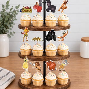 May include: A three-tiered wooden cupcake stand holding twelve cupcakes topped with white frosting and colorful sprinkles. Each cupcake features a paper topper depicting various characters and scenes from the animated film Tarzan.