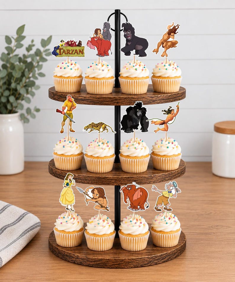 May include: A three-tiered wooden cupcake stand holding twelve cupcakes topped with white frosting and colorful sprinkles. Each cupcake features a paper topper depicting various characters and scenes from the animated film Tarzan.
