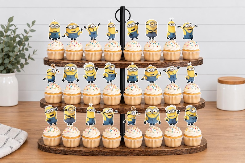 May include: A three-tiered wooden cupcake stand holding twenty-two cupcakes, each topped with a paper Minion character cutout. The cupcakes feature white frosting with colorful sprinkles in light brown paper liners, arranged on dark wood shelves.