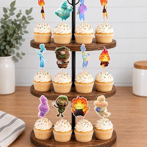 May include: A three-tiered wooden cupcake stand holding twelve cupcakes, each topped with a decorative paper cutout featuring various colourful animated characters from the movie Elemental, including Ember, Wade, and other supporting figures.