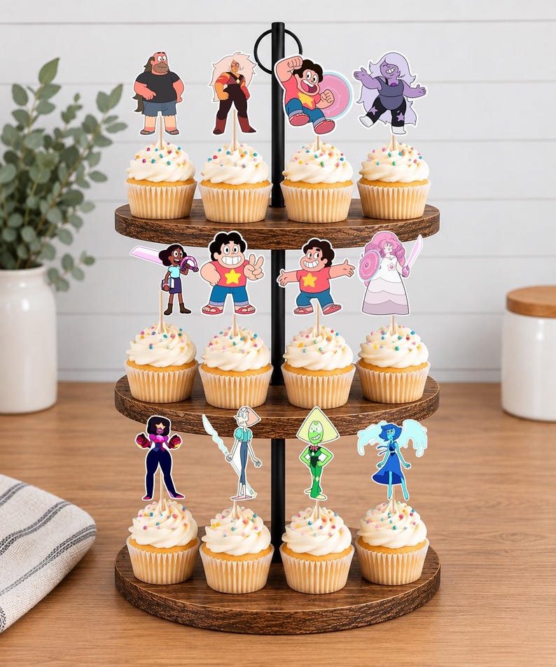 Puede incluir: Un soporte de madera para cupcakes de tres niveles con doce cupcakes, cada uno decorado con un recorte de papel de un personaje de Steven Universe. Los personajes incluyen a Steven, Garnet, Amethyst, Pearl, Rose Quartz, Peridot, Lapis Lazuli, Connie y Jasper.