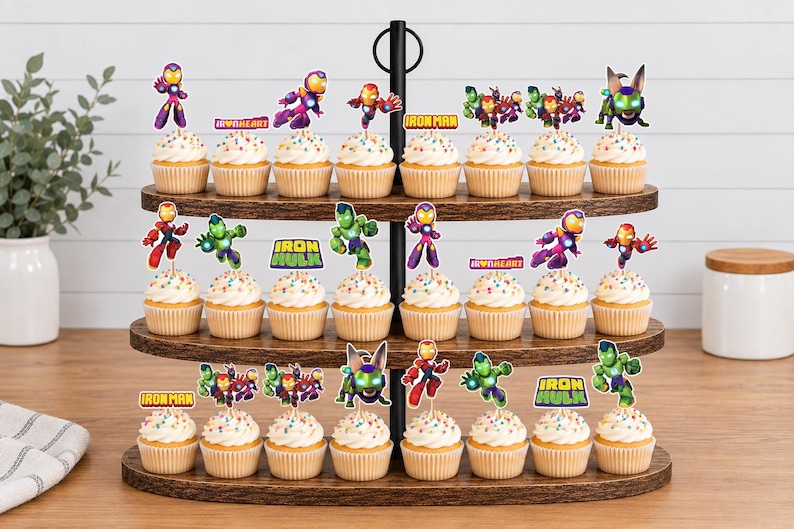 May include: A three-tiered wooden cupcake stand holding twenty-four cupcakes topped with colorful paper toppers featuring various superhero characters and text including Iron Man, Ironheart, and Iron Hulk in vibrant red, green, and purple hues.