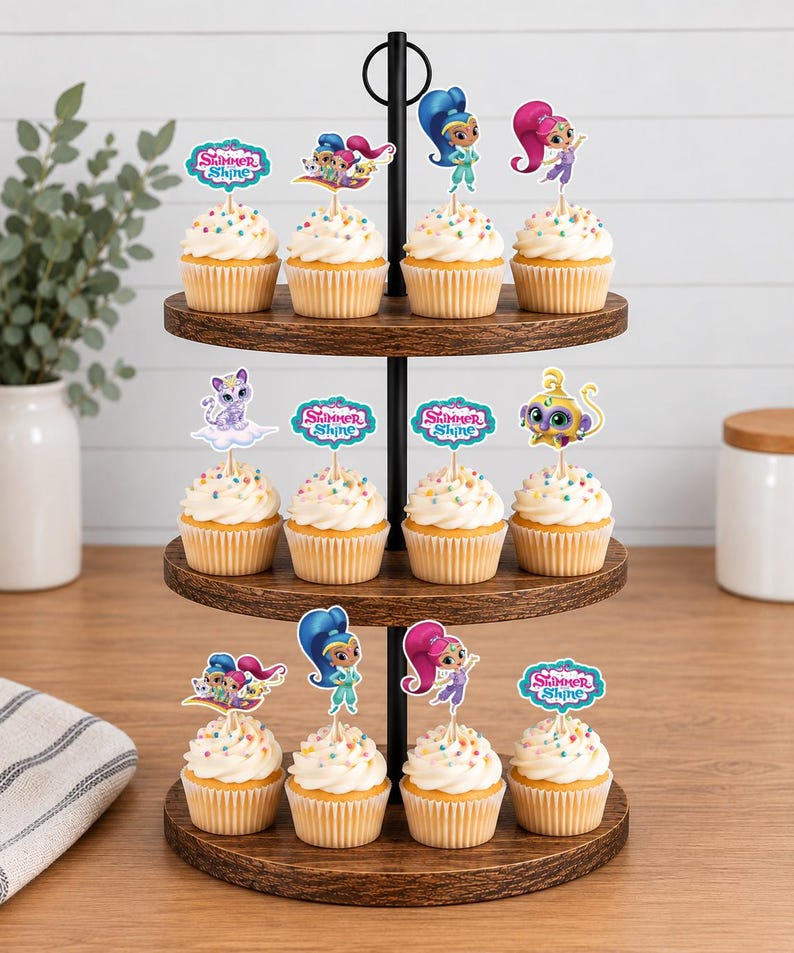 May include: A three-tiered wooden cupcake stand holding twelve cupcakes topped with white frosting, colorful sprinkles, and Shimmer and Shine character paper toppers. The toppers feature various characters, animals, and the Shimmer and Shine logo.
