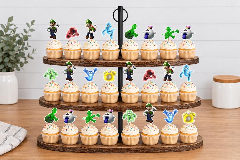 Puede incluir: Un soporte de madera para cupcakes de tres niveles con veinticuatro cupcakes, cada uno decorado con un recorte de papel que muestra personajes y fantasmas de la serie de videojuegos Luigi's Mansion, incluyendo a Luigi y varias figuras espectrales.