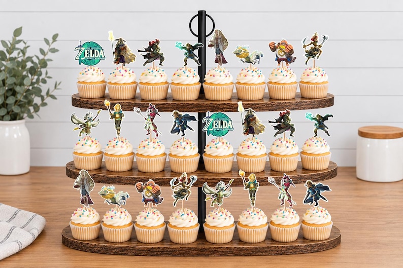 May include: A three-tiered wooden cupcake stand holding twenty-four cupcakes, each topped with a decorative paper cutout featuring characters and the Legend of Zelda logo. The cupcakes have white frosting with colourful sprinkles on a brown wooden stand.