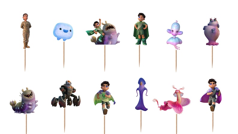 May include: A set of twelve decorative cupcake toppers featuring various animated characters and creatures in vibrant colours, each mounted on a thin wooden toothpick. The collection includes human figures, a blue blob, and several fantastical beings.