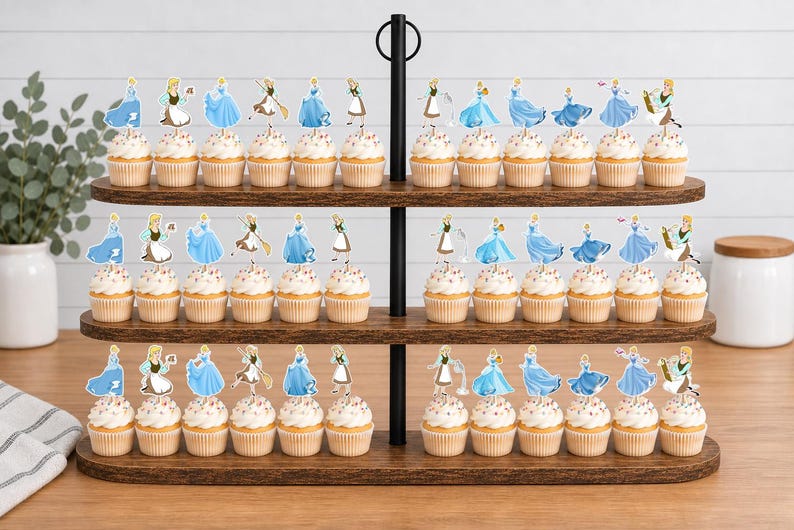 May include: A three-tiered wooden cupcake stand holding numerous cupcakes topped with paper cutouts of a character in various blue dresses and aprons. The cupcakes are arranged in rows on the dark wood shelves, featuring white frosting and light-colored liners.