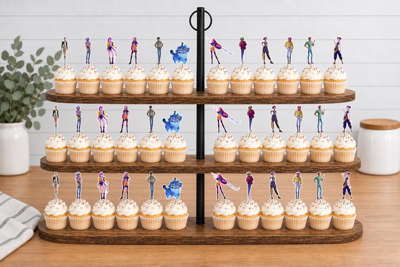 Op de afbeelding: Een houten cupcake-standaard met drie niveaus en talloze cupcakes, elk voorzien van een kleine, platte, bedrukte figuur-uitsparing. De figuren tonen diverse gestileerde personen in kleurrijke outfits en een blauw wezen, gerangschikt in rijen.