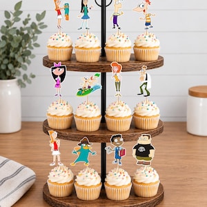 May include: A three-tiered wooden cupcake stand holding twelve cupcakes, each topped with a paper cutout of a Phineas and Ferb character. The cupcakes feature white frosting with colorful sprinkles, arranged on dark brown circular wooden trays.