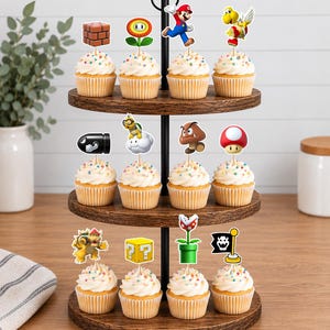 May include: A three-tiered wooden cupcake stand holding twelve cupcakes topped with colourful paper toppers featuring various Super Mario characters and icons, including Mario, Bowser, a brick block, a question block, a mushroom, and a piranha plant.