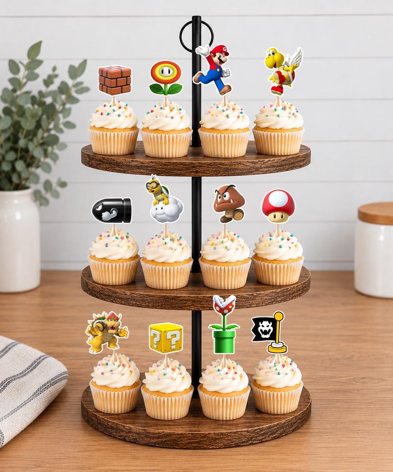 May include: A three-tiered wooden cupcake stand holding twelve cupcakes topped with colourful paper toppers featuring various Super Mario characters and icons, including Mario, Bowser, a brick block, a question block, a mushroom, and a piranha plant.