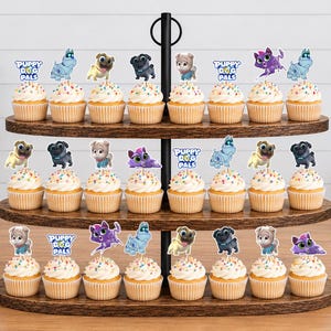 Puede incluir: Un soporte de madera de tres niveles para cupcakes con veinticuatro unidades decoradas con figuras de Puppy Dog Pals. Cada cupcake tiene un adorno de papel que muestra varios cachorros animados y el logotipo de Puppy Dog Pals.