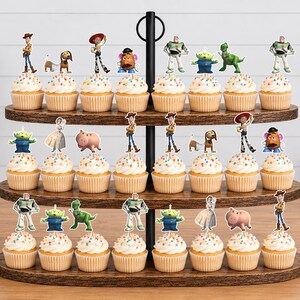 May include: A three-tiered wooden cupcake stand holding twenty-four cupcakes, each topped with a decorative paper cutout of a character from the Toy Story film franchise, including Woody, Buzz Lightyear, Jessie, Rex, Slinky Dog, and Mr. Potato Head.
