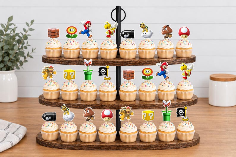 May include: A three-tiered wooden cupcake stand holding twenty-four cupcakes, each topped with a decorative paper cutout featuring various Super Mario characters and game icons like bricks, mushrooms, flowers, and question blocks.