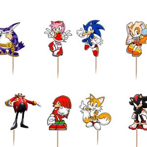 May include: A set of twelve decorative cupcake toppers featuring various Sonic the Hedgehog characters including Big the Cat, Amy Rose, Sonic, Cream the Rabbit, Super Sonic, Metal Sonic, Dr. Eggman, Knuckles, Tails, and Shadow, plus two SONIC logos.