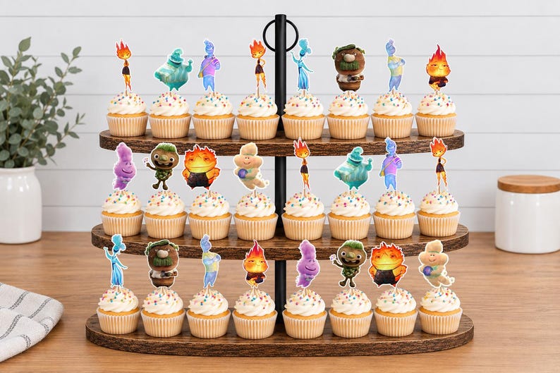 May include: A three-tiered wooden cupcake stand holding twenty-four cupcakes, each topped with a colourful character cutout from the movie Elemental. The cupcakes feature white frosting with multicoloured sprinkles, arranged on dark brown wood shelves.