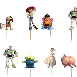 May include: A set of twelve decorative cupcake toppers featuring various animated characters including a cowboy, a cowgirl, a space ranger, a green dinosaur, a pig, a potato-shaped figure, a shepherdess, a dog with a spring body, and aliens.