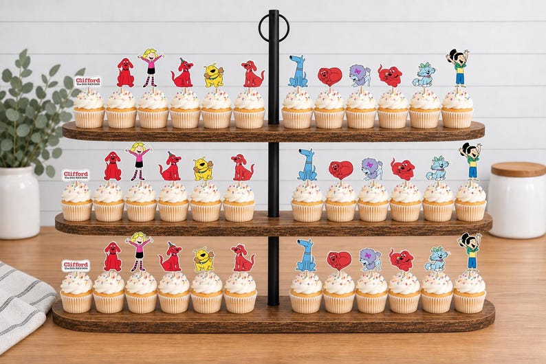 Pode incluir: Um suporte de madeira para cupcakes de tr&ecirc;s n&iacute;veis com v&aacute;rios cupcakes decorados com recortes de papel coloridos das personagens de Clifford, o c&atilde;o vermelho, incluindo Clifford, Emily Elizabeth e v&aacute;rios outros c&atilde;es.