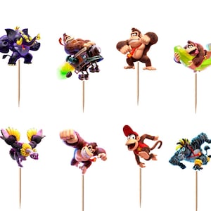 May include: A set of twelve Donkey Kong themed cupcake toppers featuring various characters in dynamic poses, each attached to a thin wooden pick. The colorful illustrations depict gorillas, monkeys, and creatures in action, including flying, swimming, and running, all set against a plain white background.