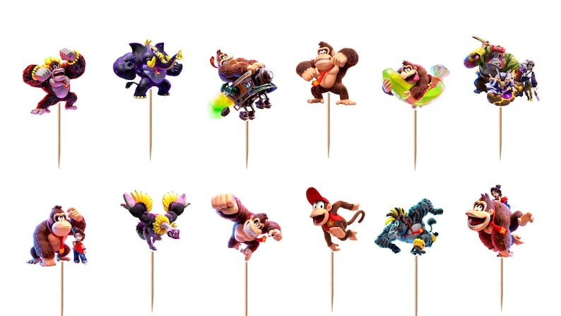 May include: A set of twelve Donkey Kong themed cupcake toppers featuring various characters in dynamic poses, each attached to a thin wooden pick. The colorful illustrations depict gorillas, monkeys, and creatures in action, including flying, swimming, and running, all set against a plain white background.