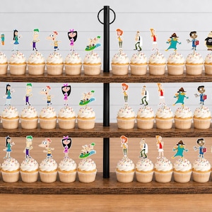 May include: A three-tiered wooden cupcake stand holding numerous cupcakes topped with colorful paper cutouts of Phineas and Ferb characters, including Phineas, Ferb, Isabella, Candace, Perry the Platypus, and other figures from the animated series.
