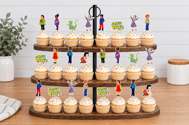 May include: A three-tiered wooden cupcake stand holding twenty-four cupcakes, each topped with a colorful paper cutout featuring characters and a yellow school bus from the Magic School Bus series, arranged in rows on the dark brown wooden shelves.