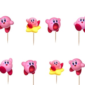 May include: A set of twelve pink Kirby character cupcake toppers, each attached to a thin wooden pick. The figures display various expressions and poses, including some riding yellow stars, with round bodies, red feet, and blue eyes.
