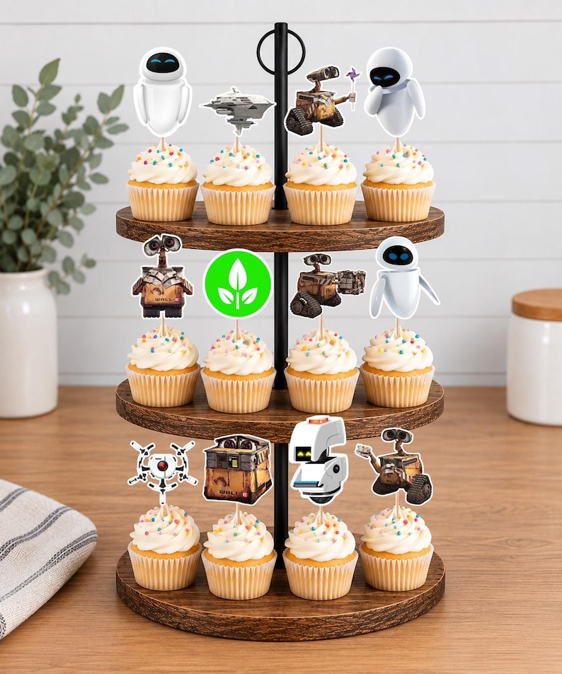 May include: A three-tiered wooden cupcake stand holding twelve cupcakes topped with white frosting and colorful sprinkles. Each cupcake features a paper topper depicting characters and icons from the movie Wall-E, including robots, a spaceship, and a green leaf symbol.